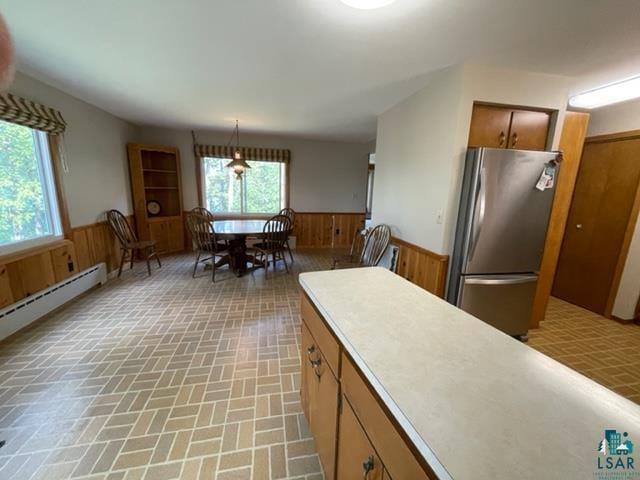 kitchen with stainless steel refrigerator, decorative light fixtures, wooden walls, and a notable chandelier