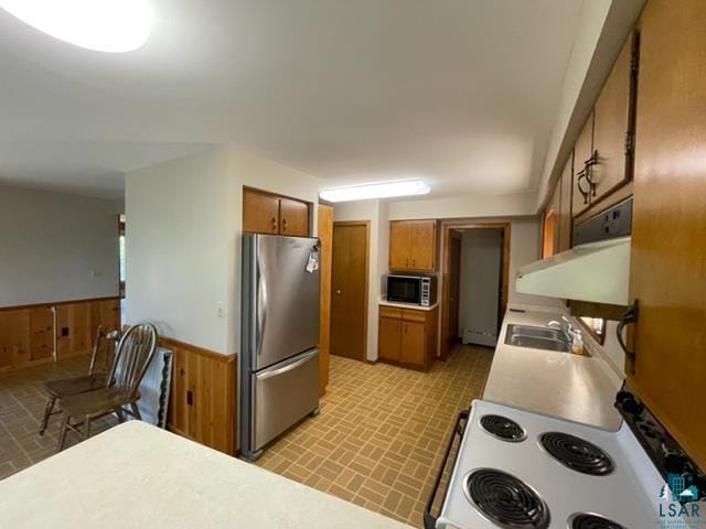 kitchen featuring appliances with stainless steel finishes, wood walls, and sink