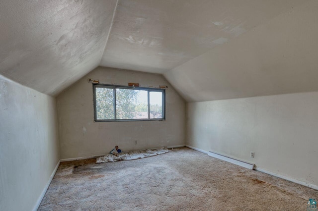 bonus room featuring a baseboard heating unit, vaulted ceiling, a textured ceiling, and light colored carpet