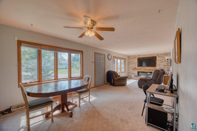 dining area with a wealth of natural light, ceiling fan, light carpet, and a fireplace