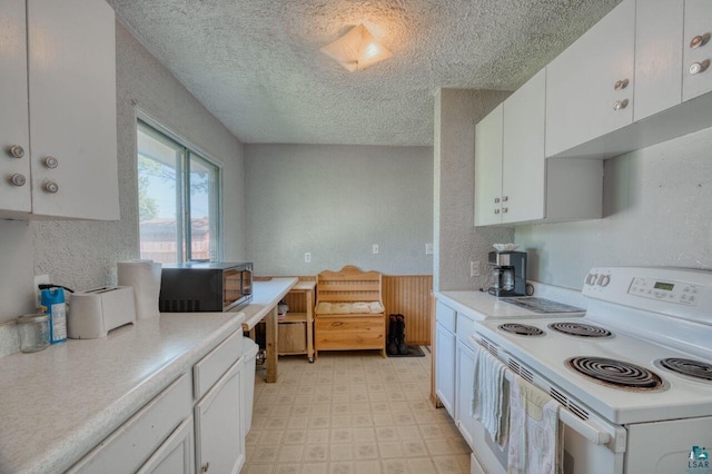 kitchen featuring a textured ceiling, electric range, and white cabinetry