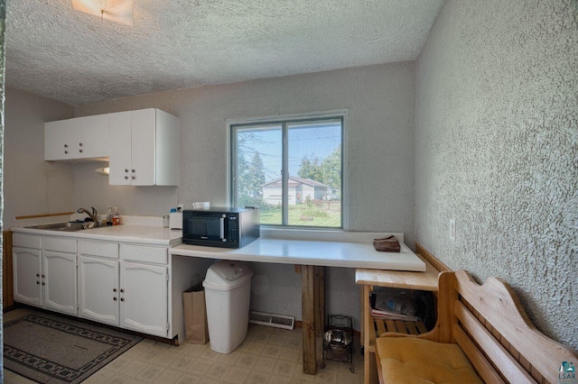 kitchen featuring a textured ceiling, sink, and white cabinetry