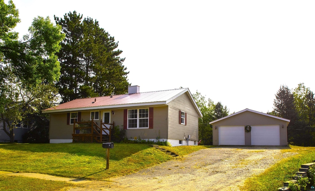 ranch-style home with a garage, a front lawn, and an outbuilding