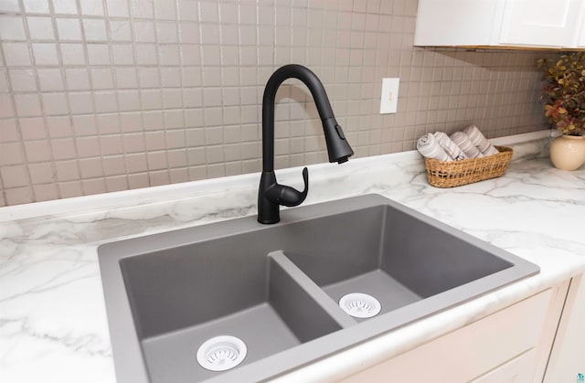 details featuring sink, light stone countertops, and white cabinets