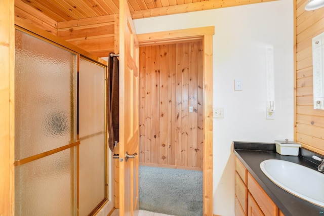 bathroom featuring wooden ceiling, vanity, a shower with shower door, and wooden walls