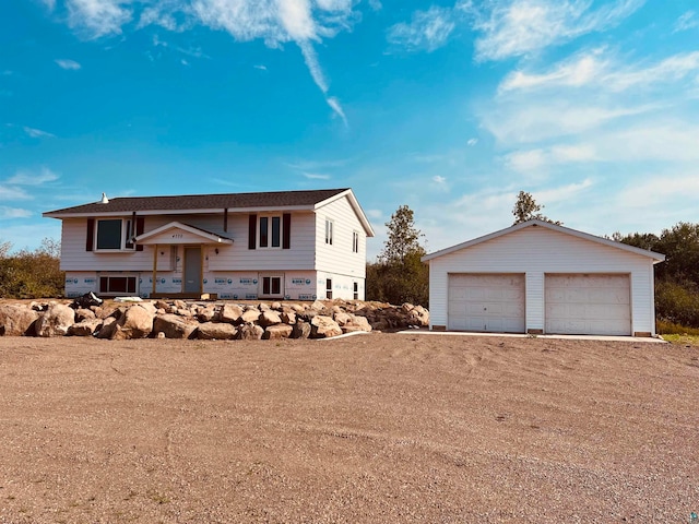 bi-level home with a garage and an outbuilding