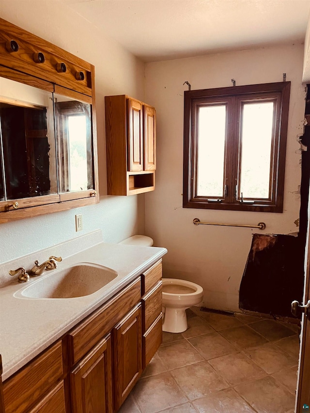 bathroom with vanity, tile patterned flooring, toilet, and a wealth of natural light