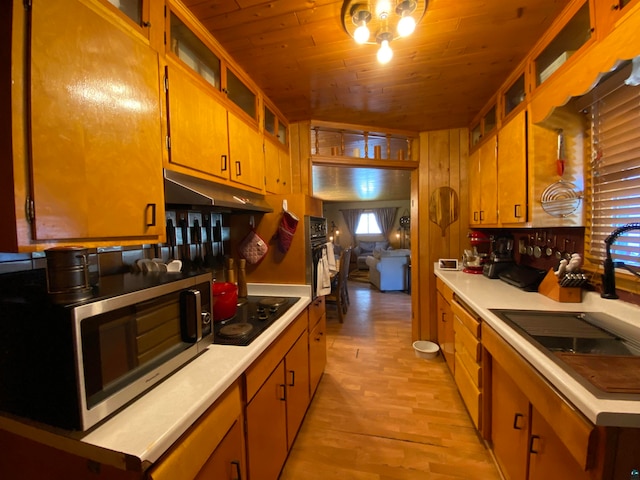 kitchen featuring wood ceiling, sink, wooden walls, black electric cooktop, and light wood-type flooring