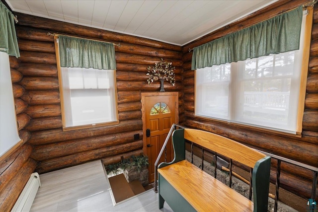 interior space with light wood-type flooring, baseboard heating, and rustic walls