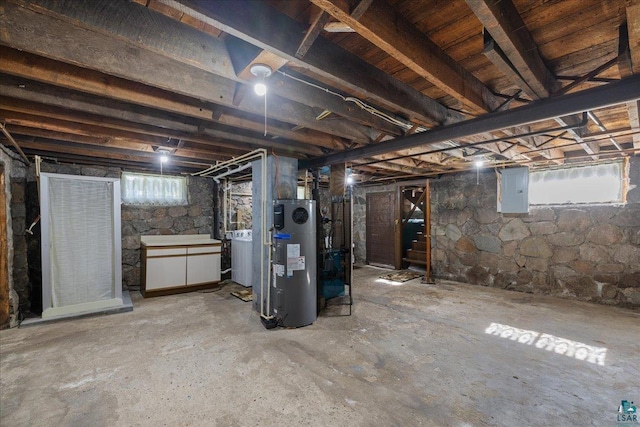 basement featuring heat pump water heater, washer / clothes dryer, and electric panel