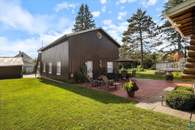 exterior space with a patio, an outdoor structure, a deck, and a yard