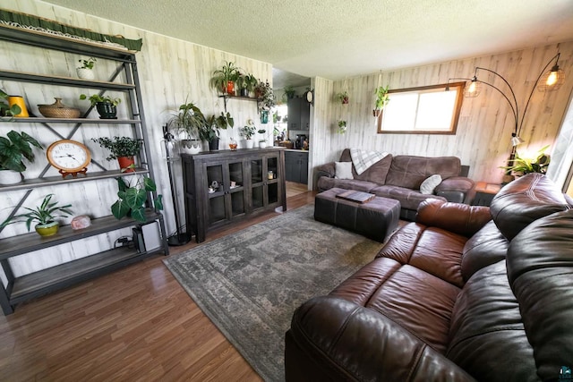 living room featuring a textured ceiling, wooden walls, and dark wood-type flooring