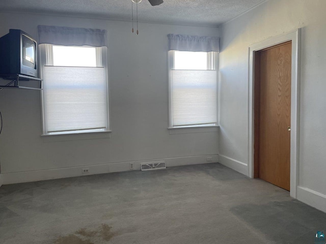 interior space with a textured ceiling, carpet, and ceiling fan