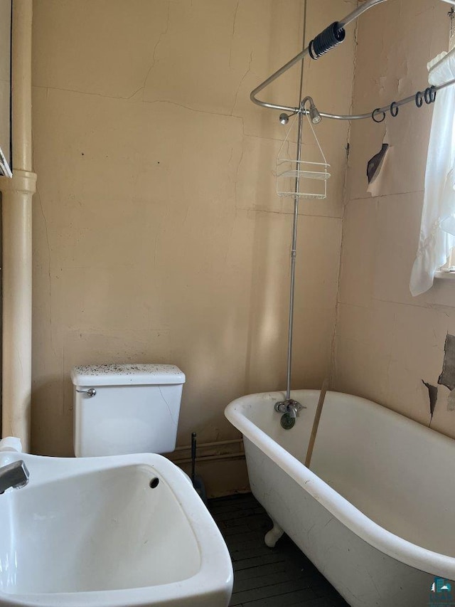 bathroom with a tub to relax in and toilet