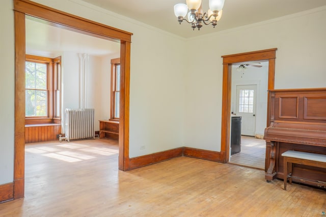 spare room with radiator, light wood-type flooring, crown molding, and plenty of natural light