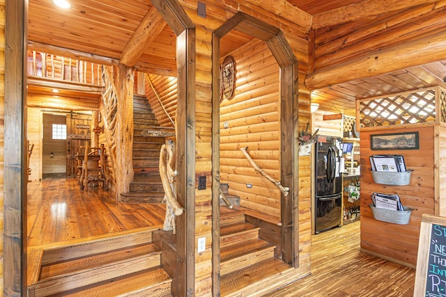 stairs featuring wooden ceiling, wood-type flooring, and log walls