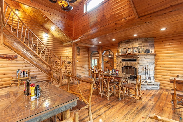 dining area with wooden ceiling, a stone fireplace, and rustic walls