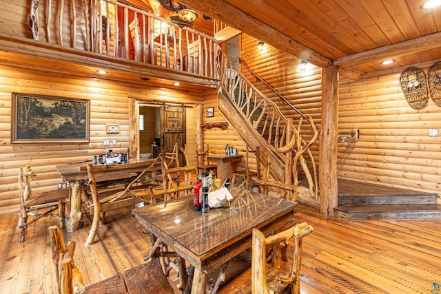 dining space featuring wood ceiling, beamed ceiling, rustic walls, and hardwood / wood-style flooring