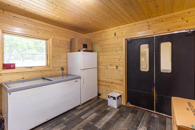 kitchen with dark wood-type flooring, white fridge, wooden ceiling, fridge, and wooden walls