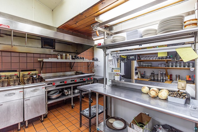 kitchen with stainless steel counters, light tile patterned flooring, and tasteful backsplash