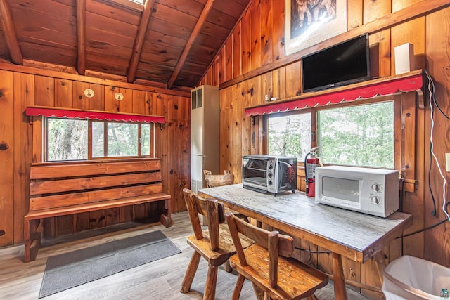 kitchen featuring light wood-type flooring, vaulted ceiling with beams, wood ceiling, and wooden walls