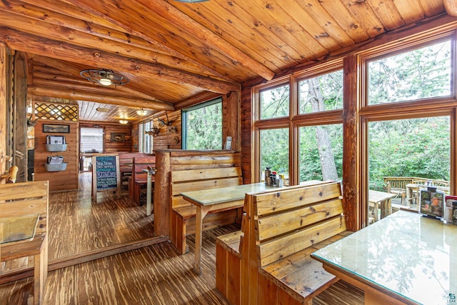 dining space with wooden walls, vaulted ceiling, hardwood / wood-style flooring, and a healthy amount of sunlight