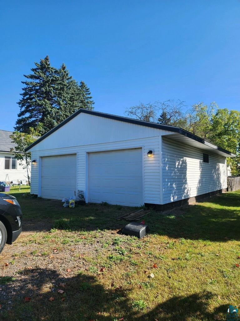 view of side of property with a lawn, an outdoor structure, and a garage