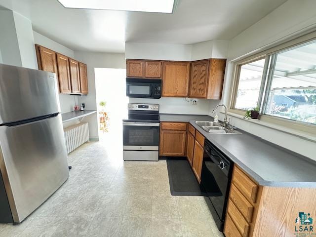 kitchen with radiator heating unit, black appliances, and sink