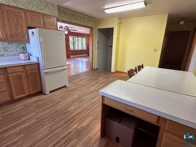 kitchen with light wood-type flooring, tasteful backsplash, white fridge, baseboard heating, and ceiling fan