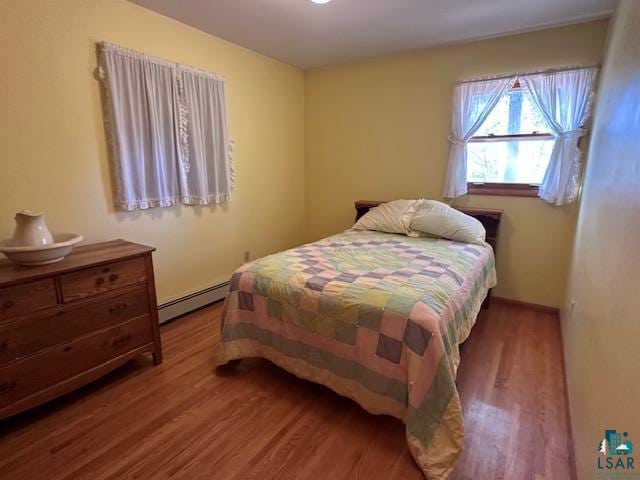 bedroom with a baseboard radiator and hardwood / wood-style flooring