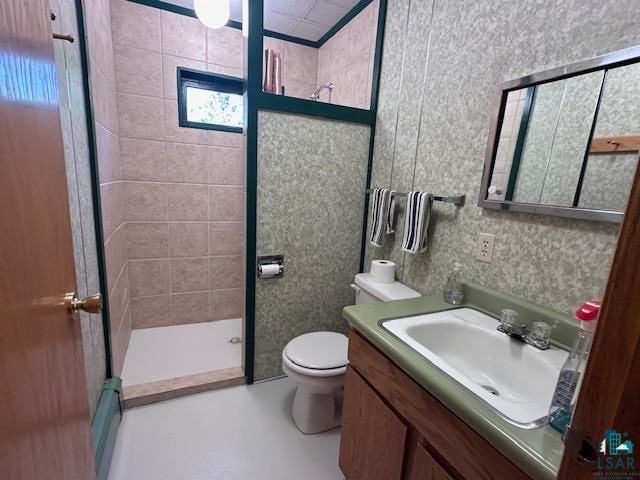 bathroom with a tile shower, vanity, and toilet