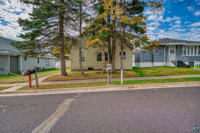 bungalow-style house featuring central AC unit and a front lawn