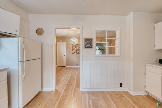 kitchen with white cabinets, white refrigerator, light hardwood / wood-style flooring, and a chandelier