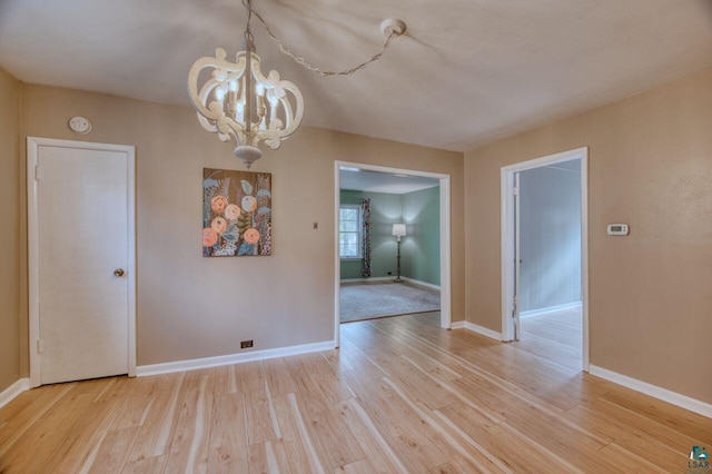 unfurnished dining area with a notable chandelier and light wood-type flooring