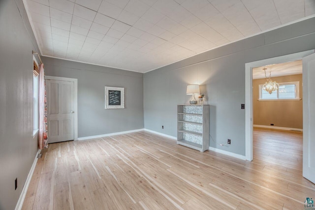 spare room with an inviting chandelier and light hardwood / wood-style flooring