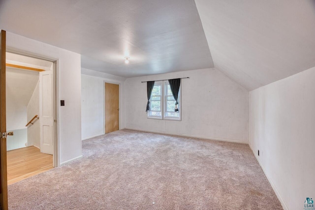 bonus room with light carpet and vaulted ceiling