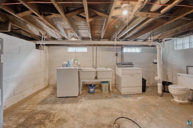 basement featuring sink, washing machine and clothes dryer, and a wealth of natural light