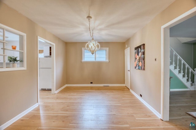 unfurnished dining area featuring light hardwood / wood-style flooring and a chandelier