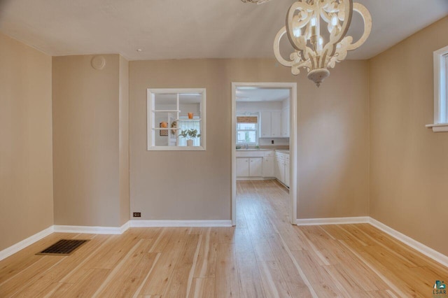 unfurnished dining area featuring light wood-type flooring and an inviting chandelier