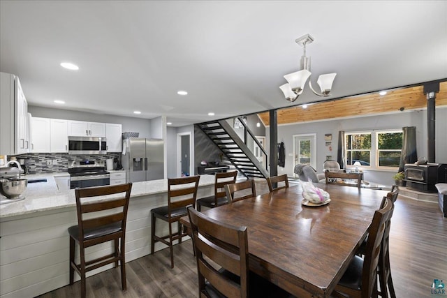 dining room featuring an inviting chandelier, dark hardwood / wood-style flooring, sink, and a wood stove