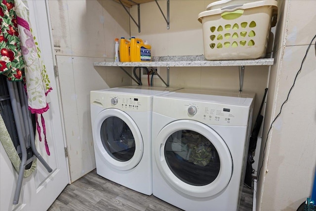 clothes washing area featuring washer and clothes dryer and light wood-type flooring