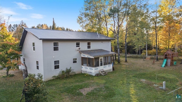 rear view of house featuring a playground, a sunroom, and a lawn