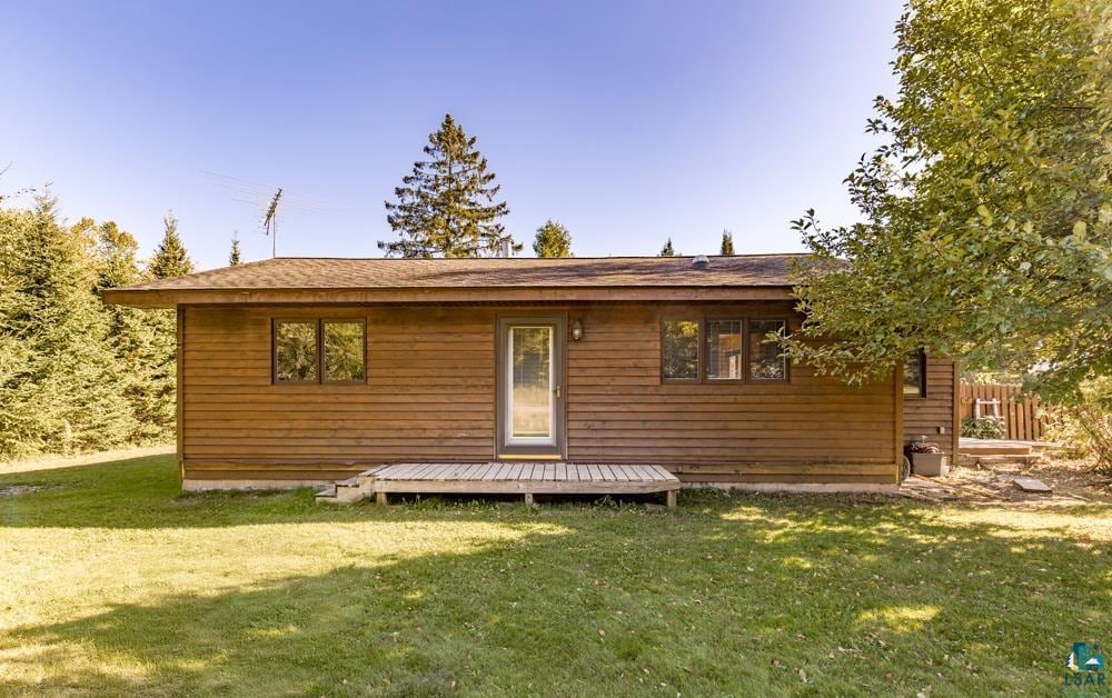 rear view of house featuring a deck and a yard