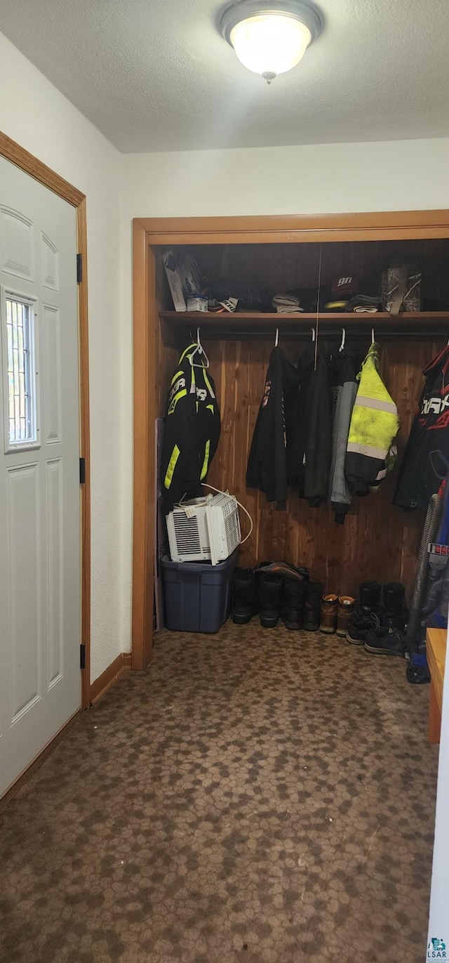 mudroom featuring a textured ceiling and dark colored carpet