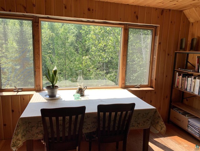 dining space featuring wooden ceiling and wood walls