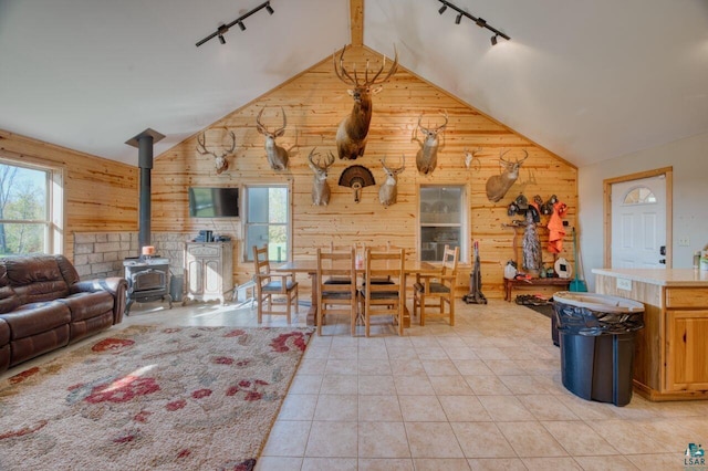 interior space with light tile patterned flooring, wooden walls, a wood stove, and rail lighting