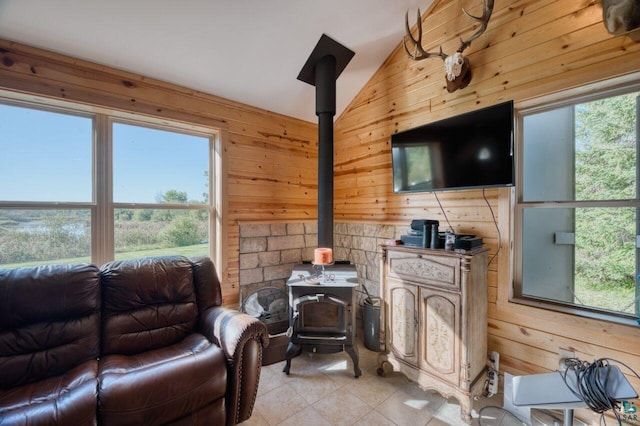 living room with a wood stove, lofted ceiling, and wooden walls