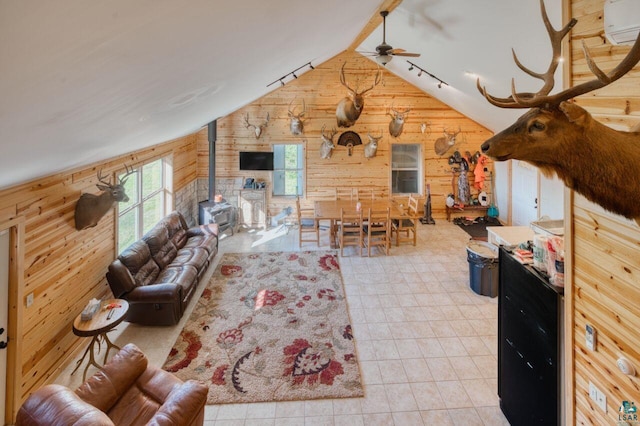 living room with ceiling fan, wooden walls, a wood stove, lofted ceiling, and a wall mounted AC