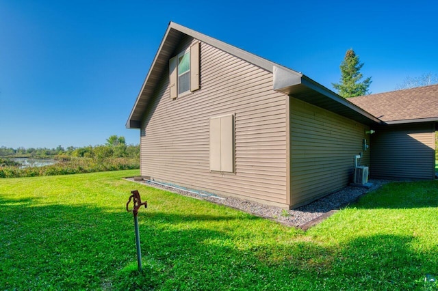 view of side of property featuring a yard and central AC