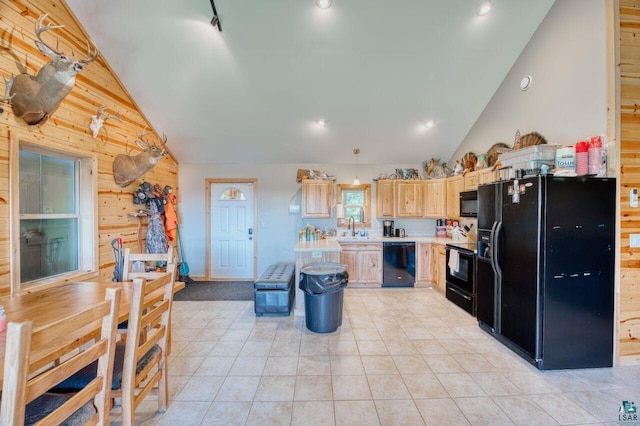 kitchen with wood walls, light brown cabinets, hanging light fixtures, black appliances, and light tile patterned floors